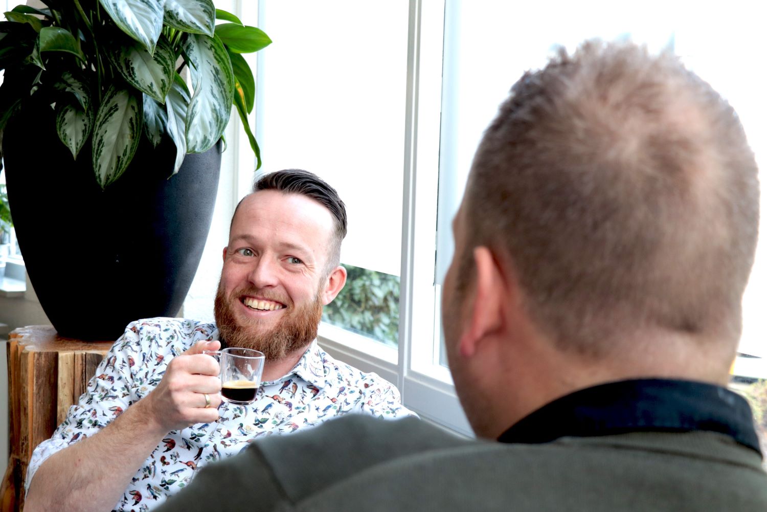 Recruiter in gesprek met sollicitant. Kopje koffie in de hand en lachen